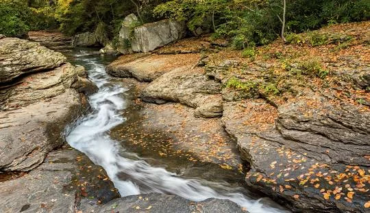 Ohiopyle State Park Waterfall – Picturesque waterfall along the Ferncliff Peninsula Trail at Ohiopyle, an adventurous places to go near me in Pennsylvania for hiking and rafting.